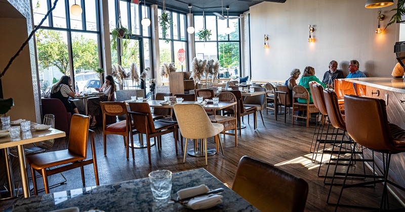 Restaurant interior, dining area with set dining tables, guests enjoying their food