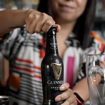 The bartender open a bottle of Guinness beer