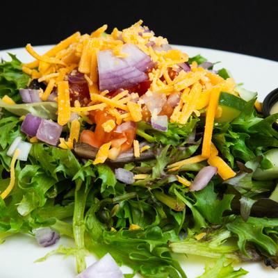 Fresh salad topped with cheese, chopped tomato and red onion.