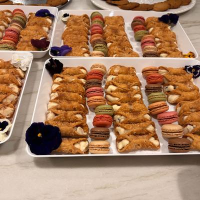 Cannoli and colorful macarons arranged on serving trays.