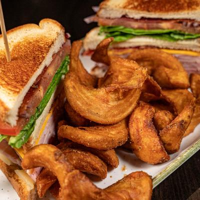 A close-up of a club sandwich with fries.