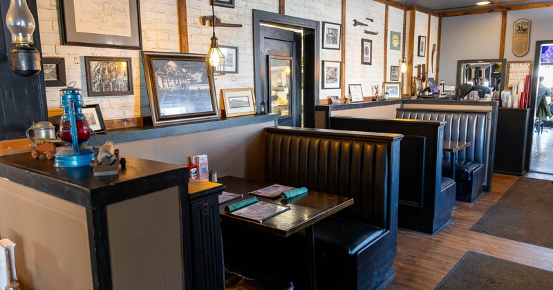 A cozy dining area - black leather booths, historical photographs on brick walls and pendant lights.
