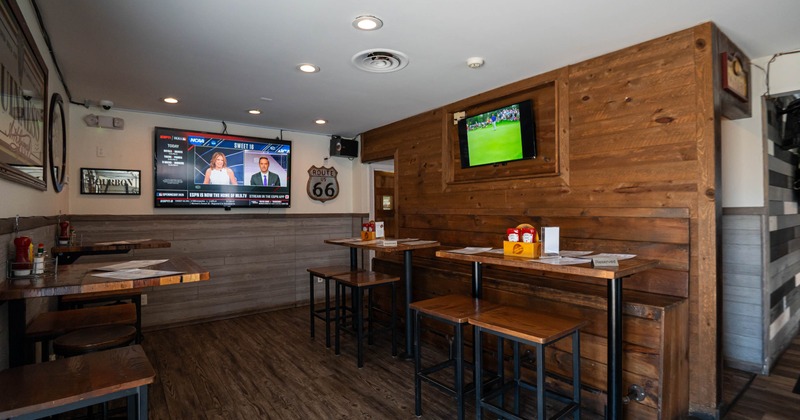 Interior, high seating tables with stools and banquette seating, wood coated walls