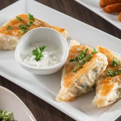 Greek spinach pie served with a side of tzatziki sauce.