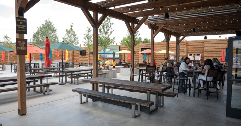 A partially covered outdoor patio, guests chatting and enjoying their drinks