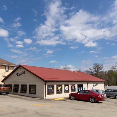 Restaurant exterior with parked cars against a blue sky with scattered clouds.