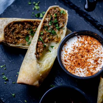 Chopped Cheese Egg Rolls sliced in half and served with a dipping sauce.