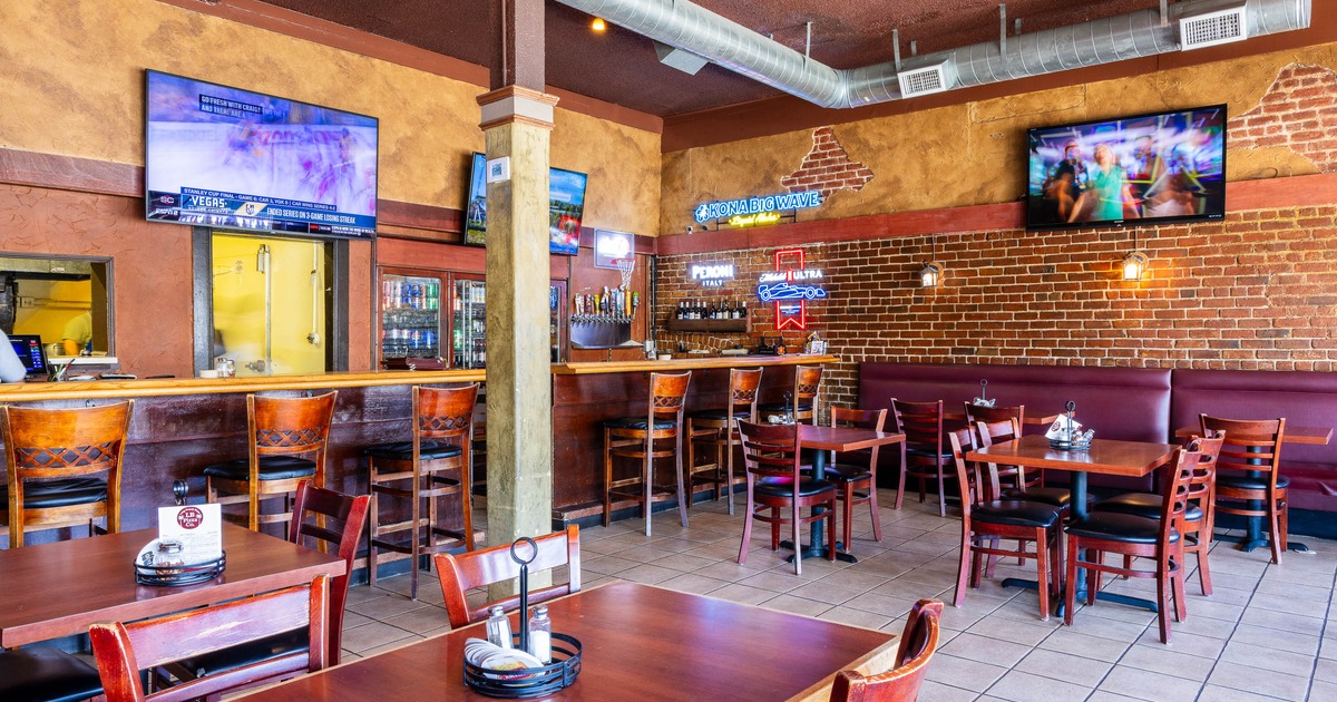 Casual sports bar interior with wooden tables and chairs, a brick wall