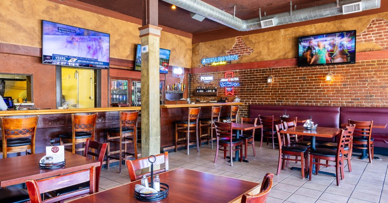 Casual sports bar interior with wooden tables and chairs, a brick wall