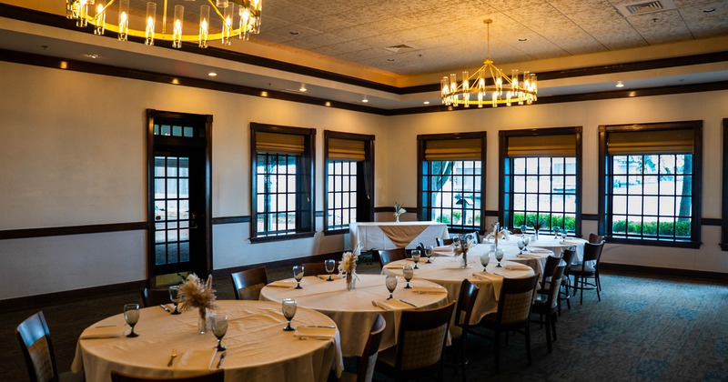 Elegant dining room with round tables, chandeliers, and large windows