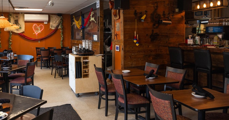Interior, dining area, wooden top tables with chairs, bar in the back, tile flooring