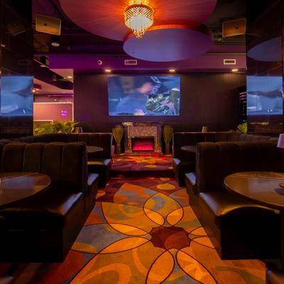 Interior space, booth seating , a fire place, a colorful abstract carpet, wall mounted screen.