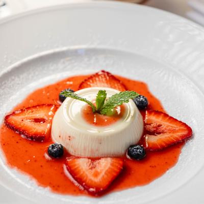 Panna cotta dessert with strawberries and mint spring garnish.
