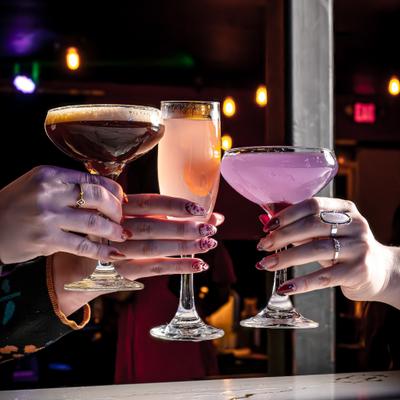 Three hands clinging glasses with cocktails.