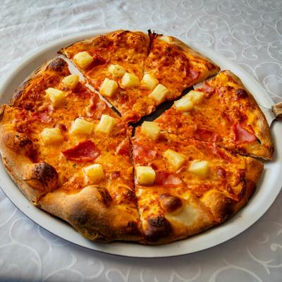 Hawaiian pizza topped with tomato sauce, mozzarella, ham and pineapple.