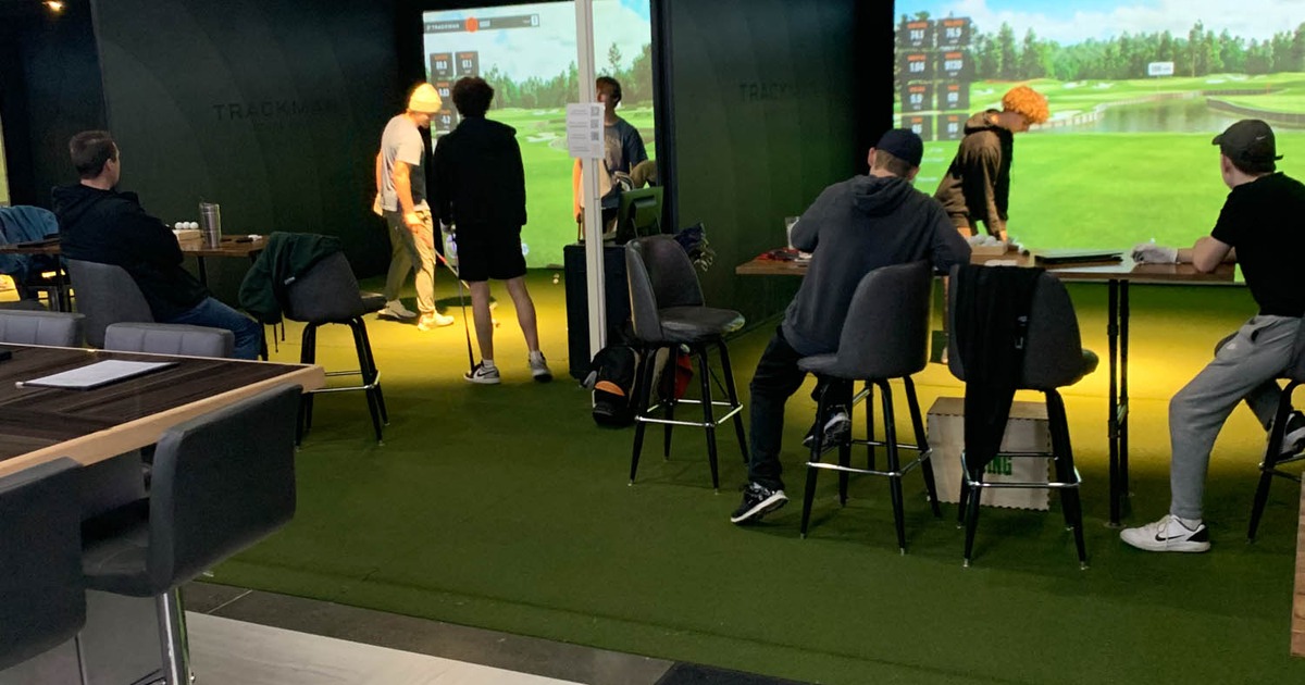 Customers playing virtual golf and sitting at tables