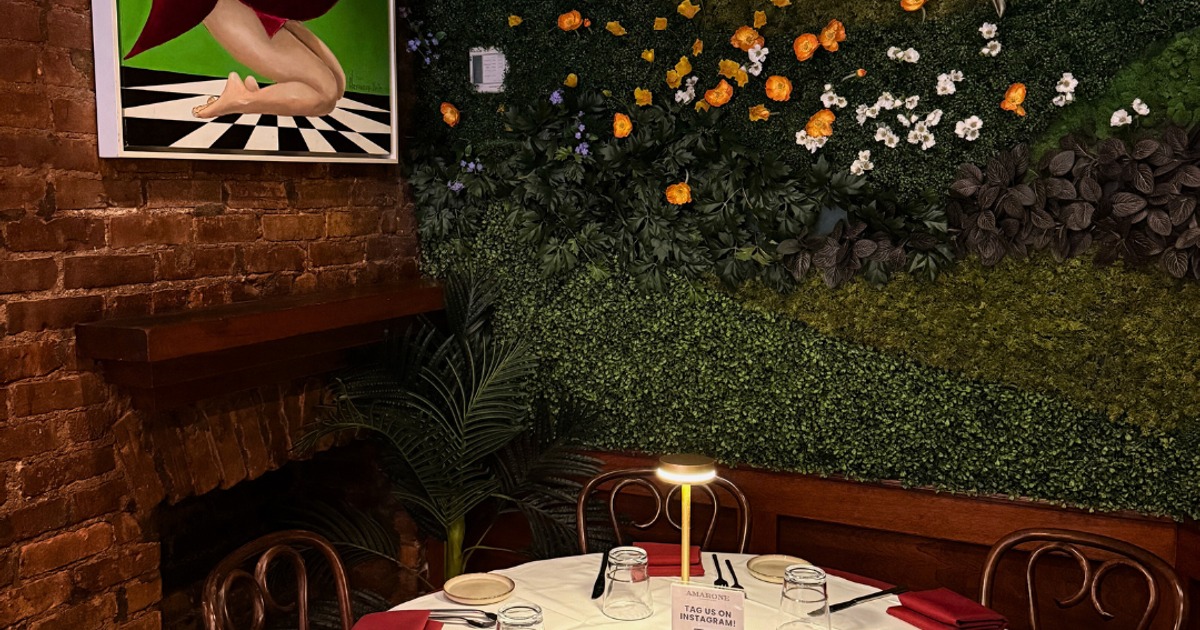 Round dining table by the green flower wall and colorful artwork