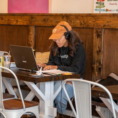 A person wearing headphones working on their laptop in a coffee shop.