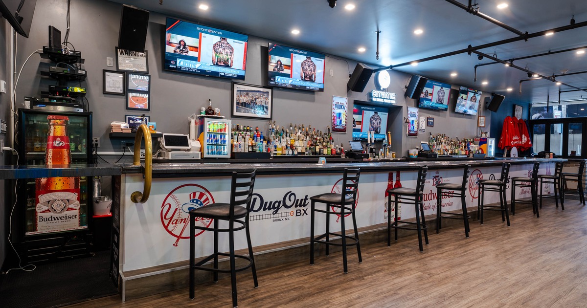 Interior of a sports bar - a long bar counter, bar stools, liquor display and multiple TVs