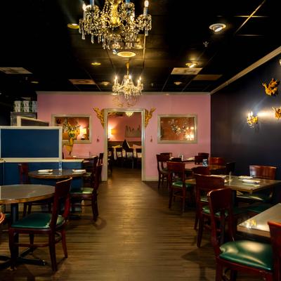Dining room featuring a dark ceiling, ornate crystal chandeliers, and pink accent walls.