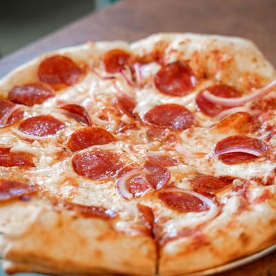 Pepperoni and red onion pizza, sliced and served.