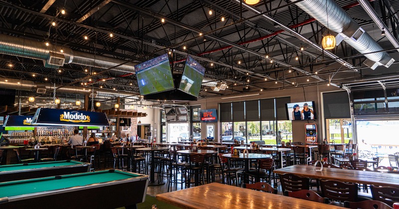 Interior of spacious sports bar, seating area, and pool tables