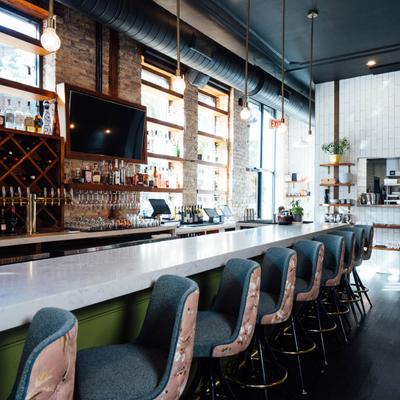 Bar area with seating, open kitchen, wine and hard liquor bottles, glassware