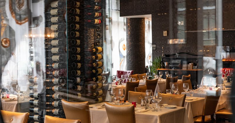 Interior, set dining tables beside a rack with wine bottles