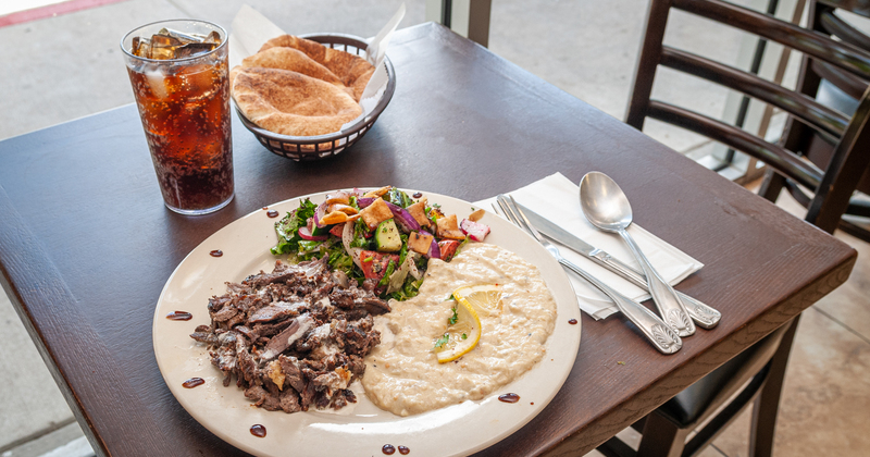 Meat with sauce, white dip, mixed vegetables on the side, snacks in the back