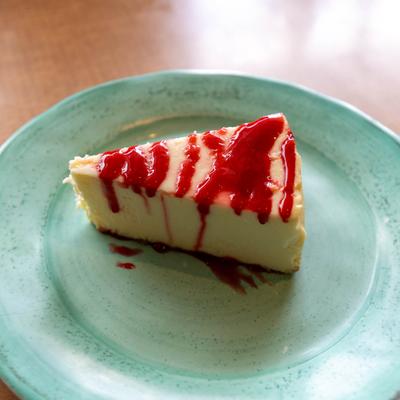 New York style cheesecake with strawberry sauce on a plate.
