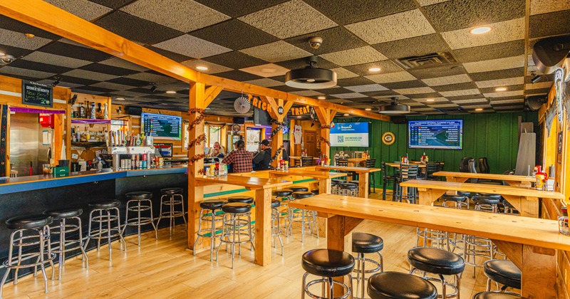 Interior, high seating area, wooden top tables with stools, long bar with stools, hardwood flooring