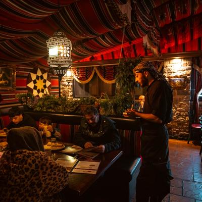 Interior, a server takes an order from a group of guests at a table.