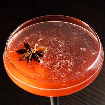 Cocktail in a coupette glass garnished with star anise pod.