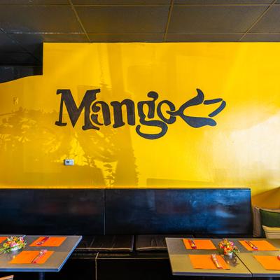 Interior with set tables and a restaurant sign on a yellow wall.