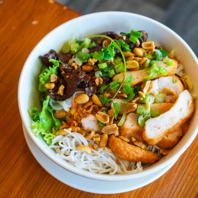 Noodle bowl featuring grilled pork, pork sausage, rice vermicelli, and peanuts.