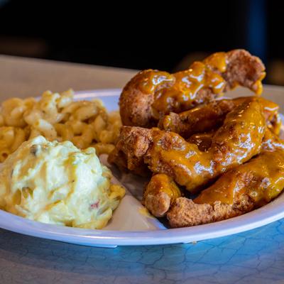 Chicken tenders served with sides of cheesy mac and potato salad