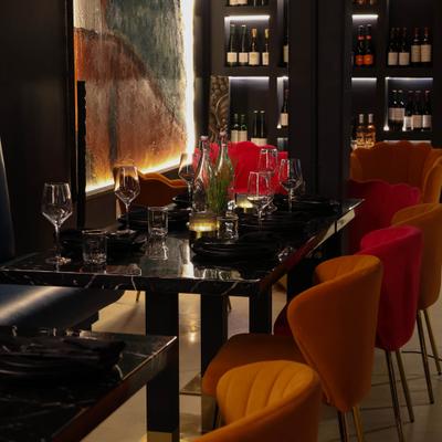 Interior featuring dark marble tables, plush re chairs, and illuminated wine racks.