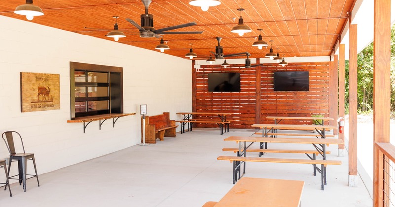 Covered patio with a wood-paneled ceiling, picnic tables, and TVs
