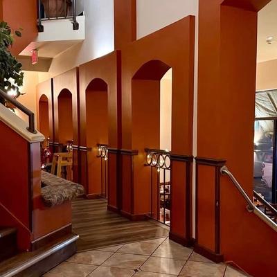Multi-level restaurant interior with warm terracotta arches and wooden stairs.