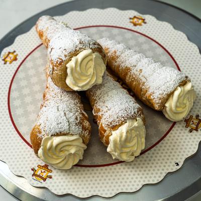 Flaky pastry cones filled with rich cream and dusted with sweet powdered sugar.