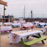 Outdoor seating area set for an event, with tablecloths on picnic tables.