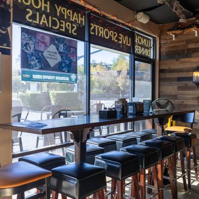 Interior featuring a long table with stools by large windows.