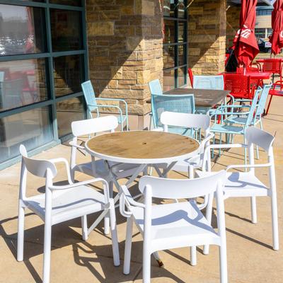 Exterior, partially covered seating area, colorful tables with chairs, parasols.