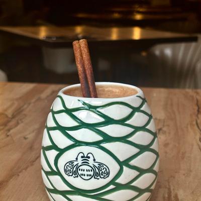 Horchata served in a ceramic tiki mug with a green agave pattern and cinnamon sticks.