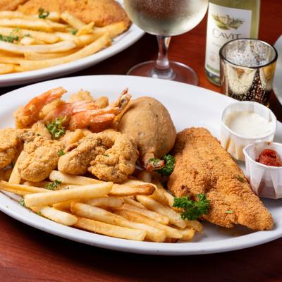 Fried seafood platter with fries and dipping sauces.
