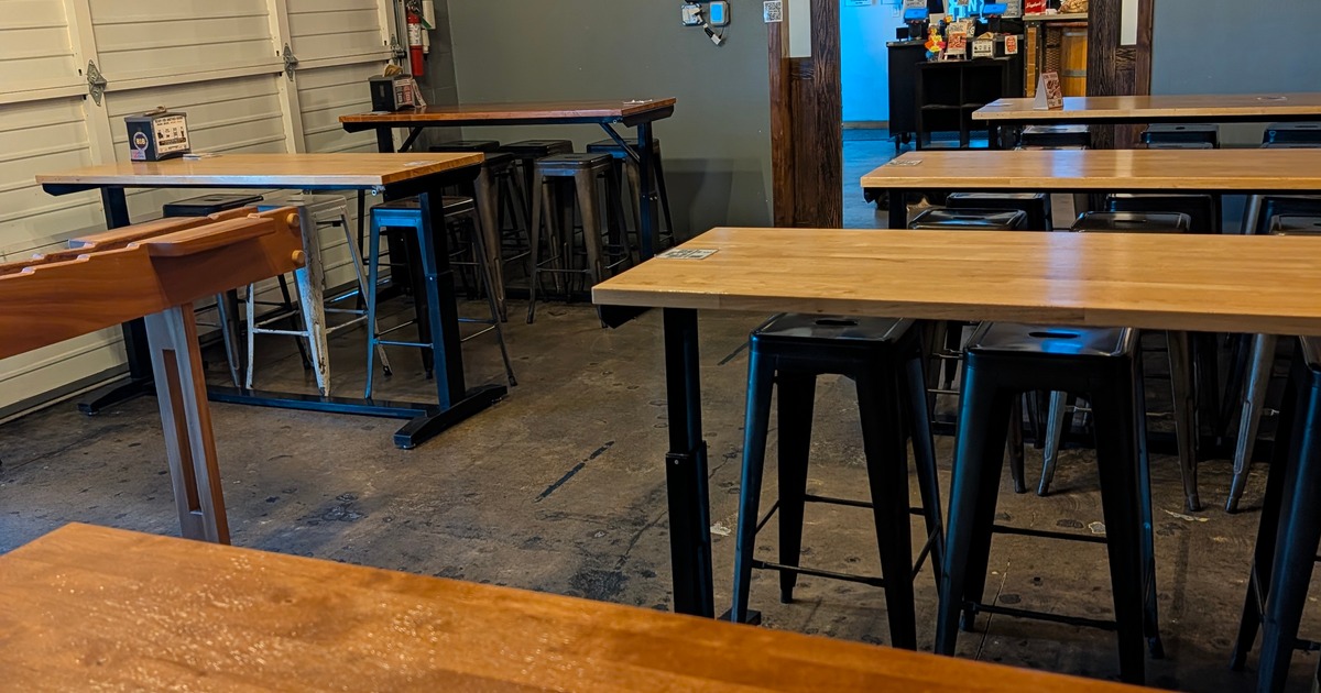Spacious brewery event room with communal tables and an open layout for private parties.