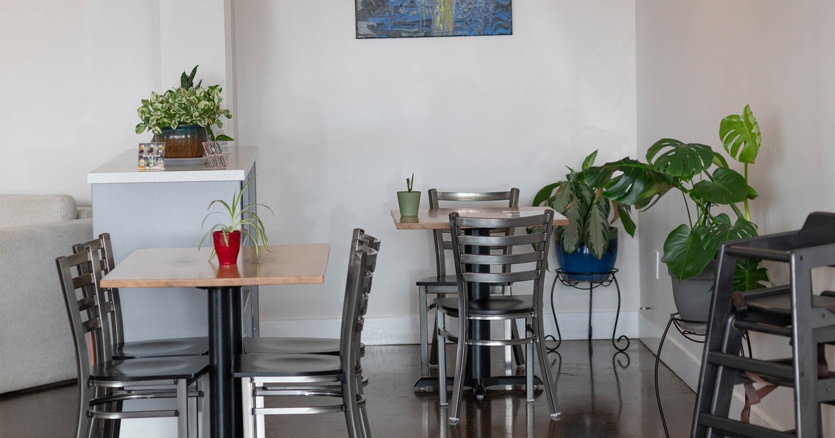 Cafe interior with small tables, metal chairs, and plants
