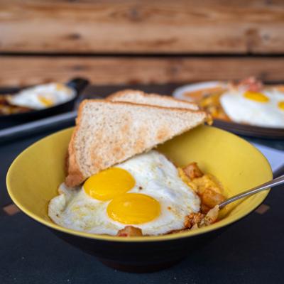 Two fried eggs with toasted bread are served in a yellow bowl on a table.