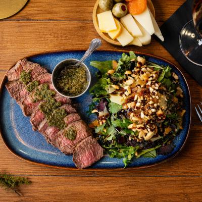 Argentinian Steak topped with chimichurri sauce and paired with a large salad.