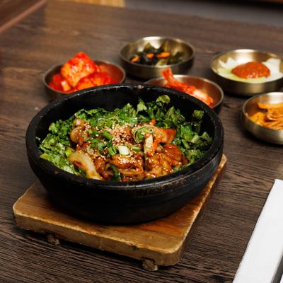 Chicken Bulgogi Hot Pot on a wooden tray, accompanied by small side dishes.